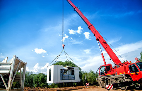 red mobile crane with premanufactured piece of building